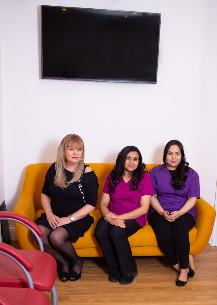 Three women sitting on a yellow sofa