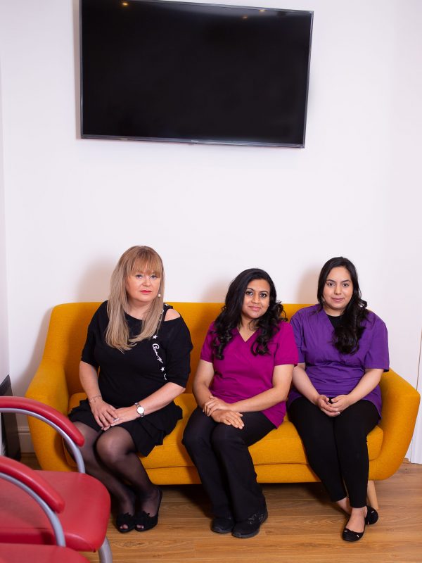 Three women sitting on a yellow sofa
